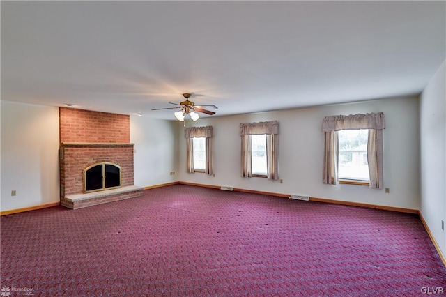 unfurnished living room with brick wall, carpet floors, a brick fireplace, and ceiling fan