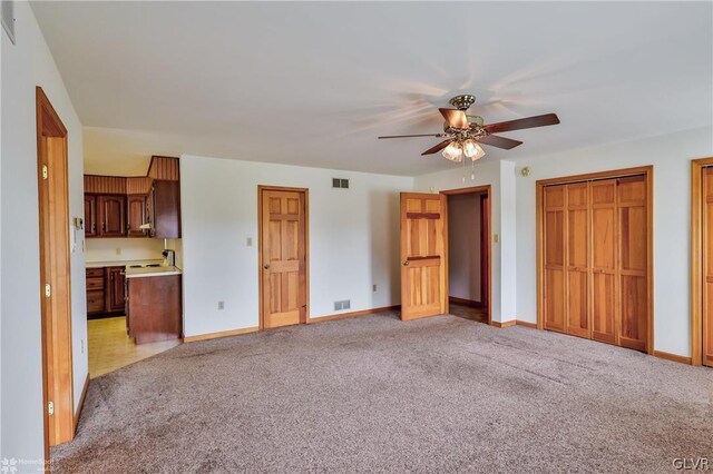 unfurnished living room featuring light colored carpet and ceiling fan