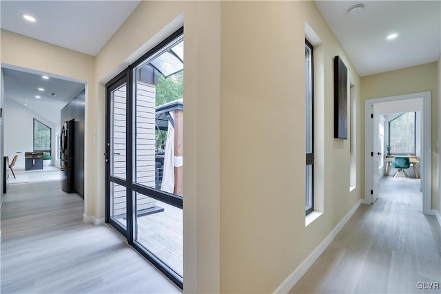 corridor with light hardwood / wood-style flooring and a wealth of natural light