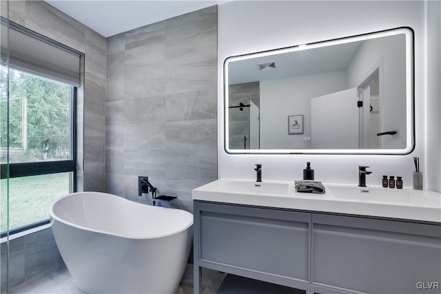 bathroom featuring independent shower and bath, tile walls, tile patterned flooring, and vanity