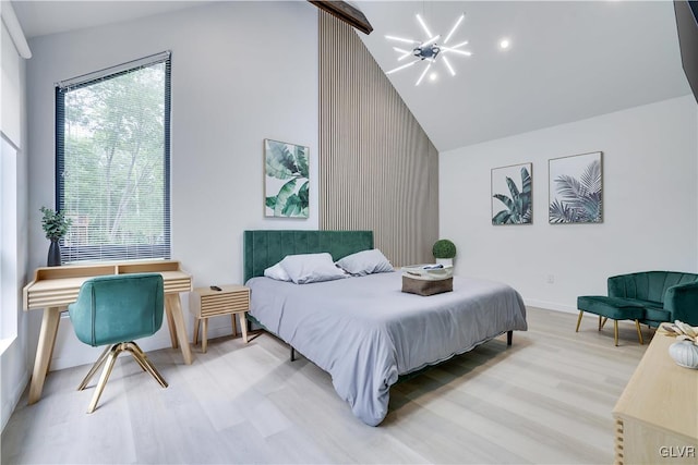 bedroom featuring an inviting chandelier, light hardwood / wood-style floors, and high vaulted ceiling