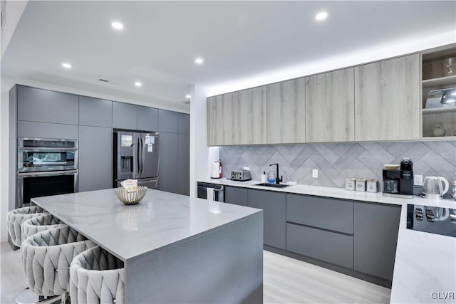 kitchen with appliances with stainless steel finishes, gray cabinetry, a center island, and tasteful backsplash