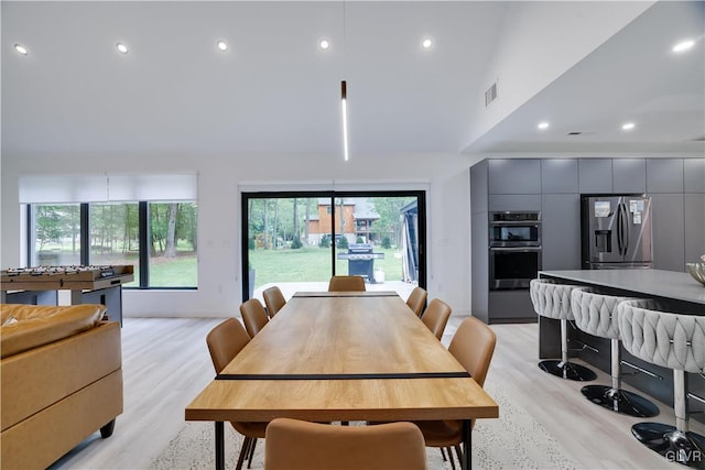 dining space with light wood-type flooring and a towering ceiling