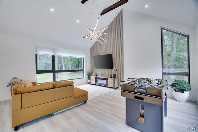 living room featuring light wood-type flooring, lofted ceiling, an inviting chandelier, and a wealth of natural light