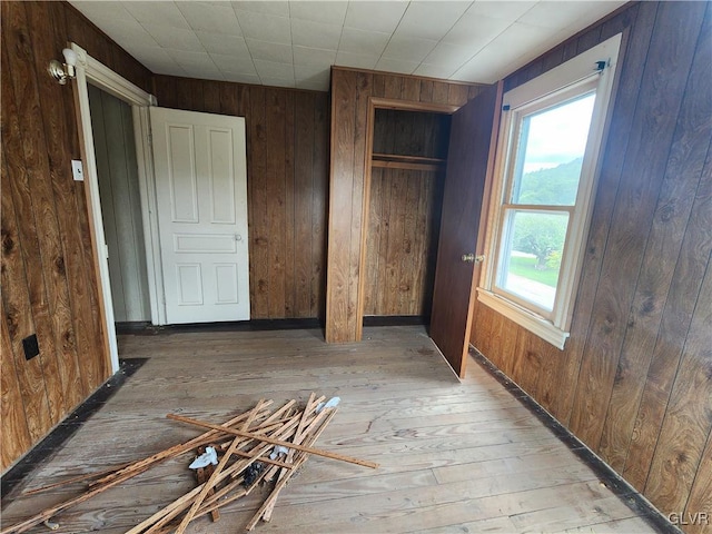 empty room with light hardwood / wood-style flooring and wooden walls