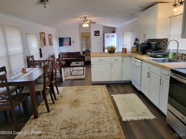 kitchen featuring white cabinetry, kitchen peninsula, dishwasher, dark hardwood / wood-style flooring, and ceiling fan