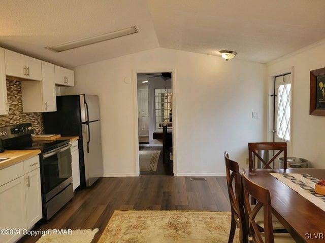 kitchen featuring tasteful backsplash, stainless steel electric range, dark hardwood / wood-style flooring, ceiling fan, and vaulted ceiling