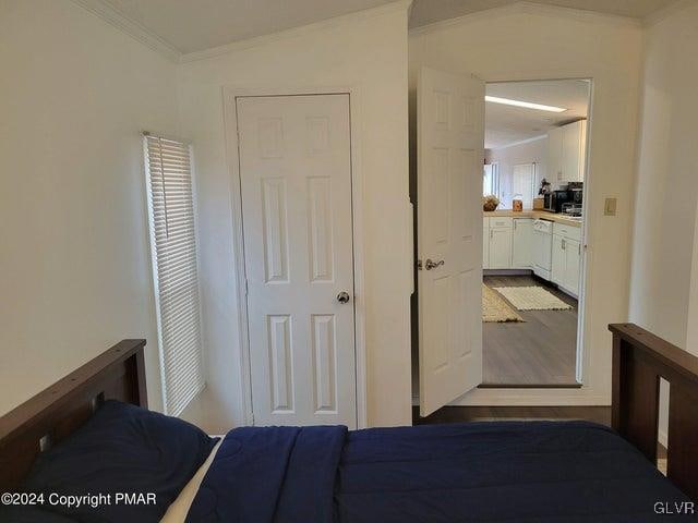 unfurnished bedroom with crown molding, light wood-type flooring, and vaulted ceiling