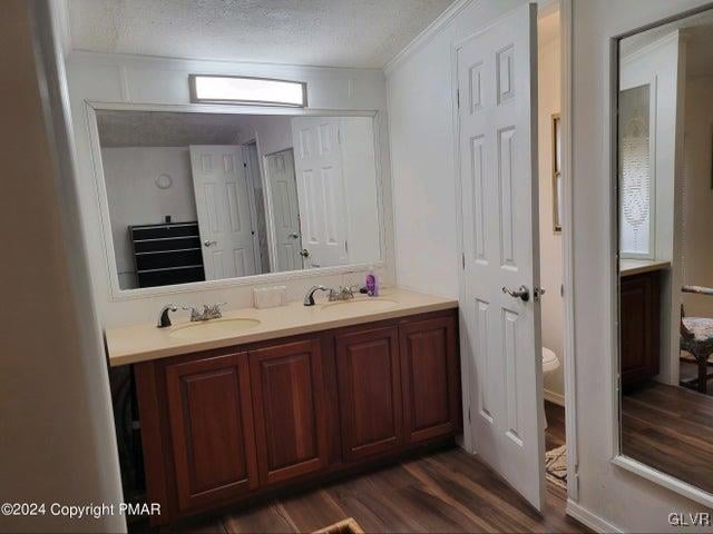 bathroom with double vanity, a textured ceiling, toilet, and hardwood / wood-style floors