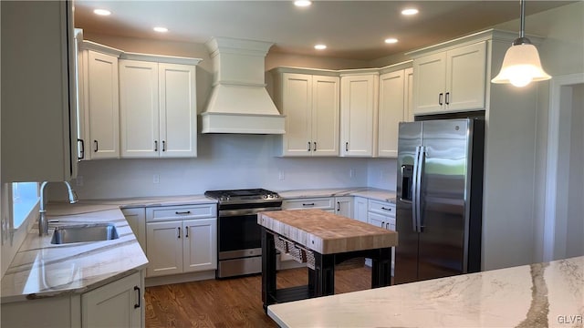 kitchen featuring appliances with stainless steel finishes, custom range hood, dark hardwood / wood-style floors, sink, and pendant lighting