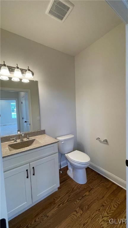 bathroom featuring toilet, hardwood / wood-style flooring, and vanity