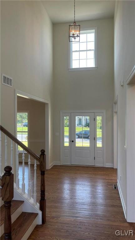 foyer entrance with a high ceiling, hardwood / wood-style floors, and a chandelier