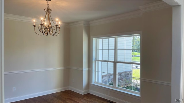 spare room with plenty of natural light, dark wood-type flooring, a chandelier, and ornamental molding