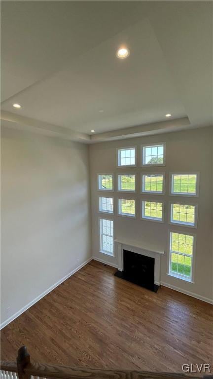 unfurnished living room with a tray ceiling and dark wood-type flooring