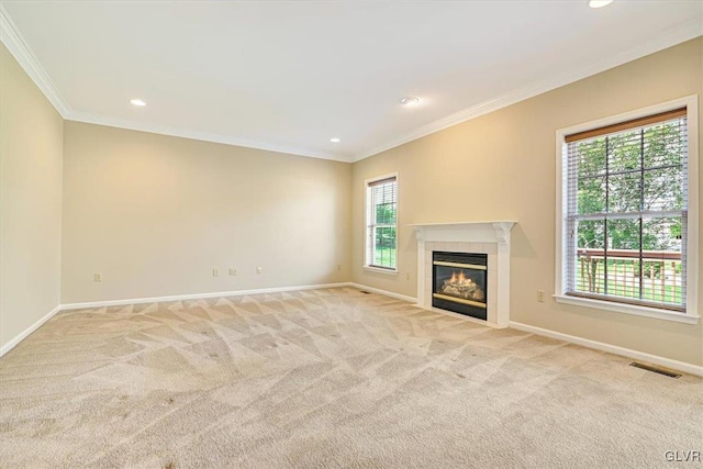 unfurnished living room featuring ornamental molding, light carpet, a healthy amount of sunlight, and a tiled fireplace