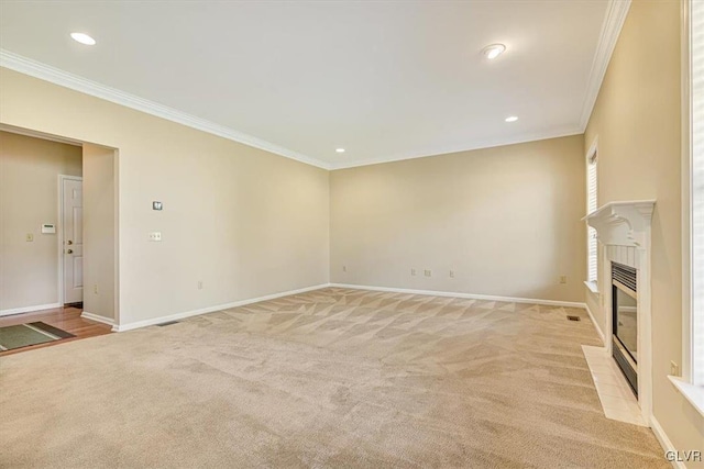 unfurnished living room with crown molding, a tile fireplace, and light colored carpet