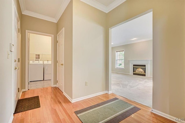 hallway with crown molding, light carpet, and separate washer and dryer