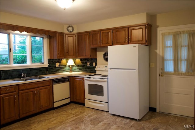 kitchen with tasteful backsplash, white appliances, brown cabinetry, and a sink