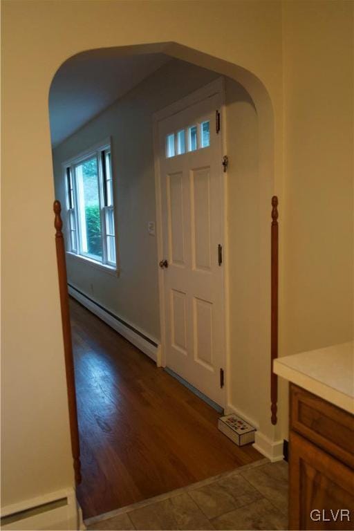 entryway with a baseboard heating unit, arched walkways, dark wood-style flooring, and baseboard heating