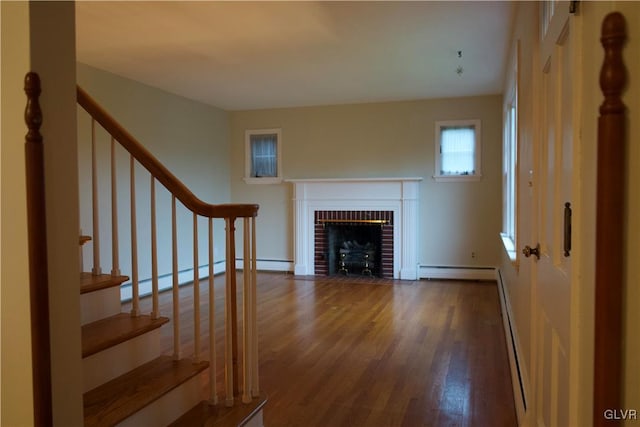 unfurnished living room with a baseboard radiator, stairway, wood finished floors, baseboard heating, and a fireplace