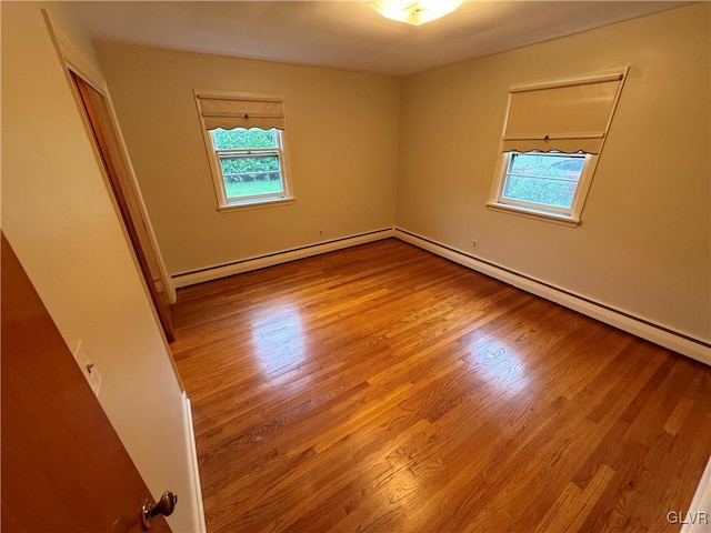 unfurnished room featuring a baseboard radiator, a wealth of natural light, and wood finished floors