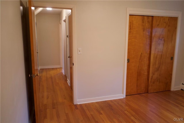 hallway featuring light wood-style flooring and baseboards