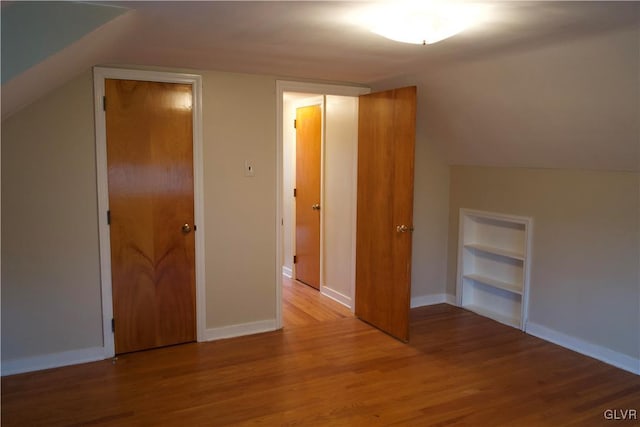 bonus room with baseboards, wood finished floors, and built in features