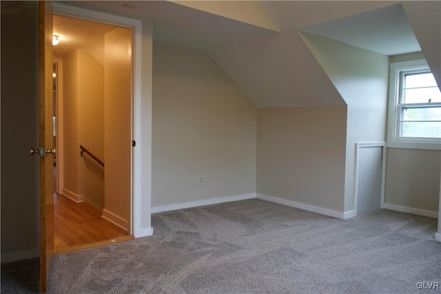 additional living space featuring baseboards, vaulted ceiling, and carpet flooring