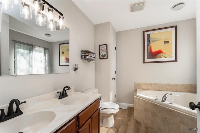 bathroom with tiled tub, dual vanity, toilet, and hardwood / wood-style flooring