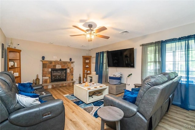 living room with a stone fireplace, ceiling fan, and hardwood / wood-style flooring