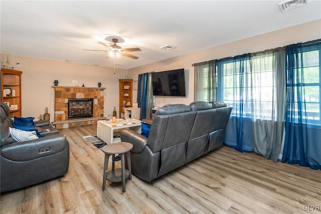 living room with a fireplace, a healthy amount of sunlight, light wood-type flooring, and ceiling fan