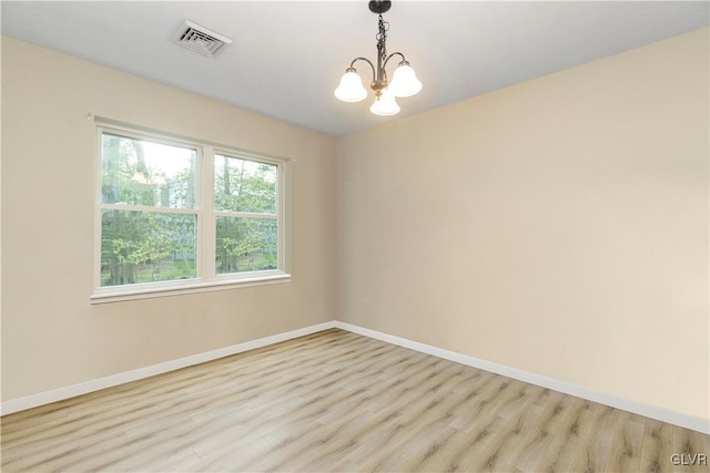 unfurnished room with light wood-type flooring and a chandelier