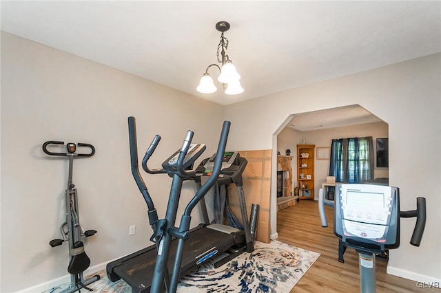 workout area with light hardwood / wood-style flooring and an inviting chandelier