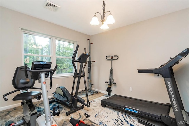 exercise room with an inviting chandelier and hardwood / wood-style flooring