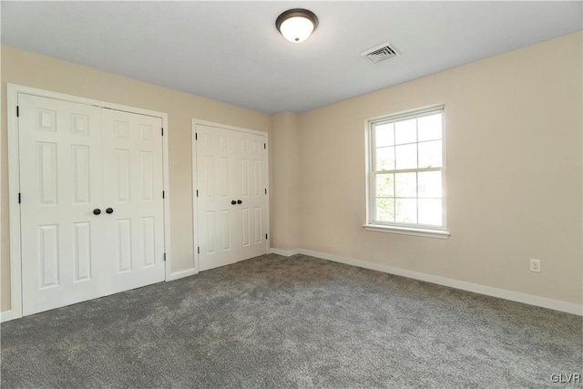 unfurnished bedroom featuring two closets and carpet floors