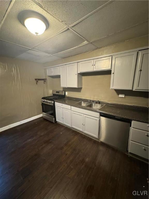 kitchen with appliances with stainless steel finishes, white cabinets, dark wood-type flooring, and sink