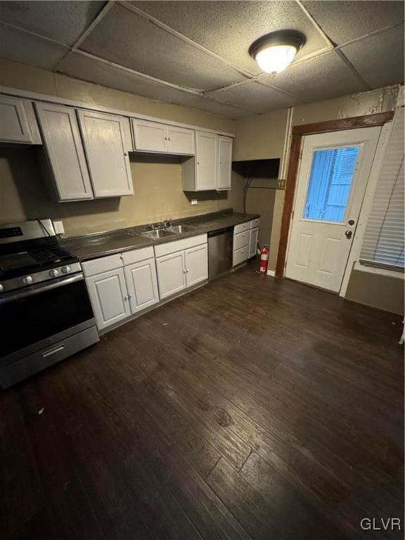 kitchen with appliances with stainless steel finishes, a paneled ceiling, dark hardwood / wood-style floors, and white cabinetry