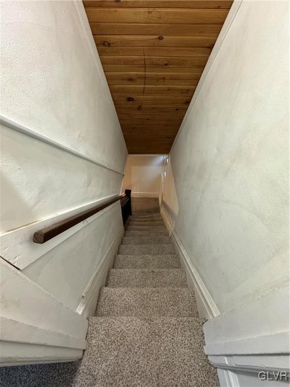 stairs featuring lofted ceiling, carpet flooring, and wood ceiling