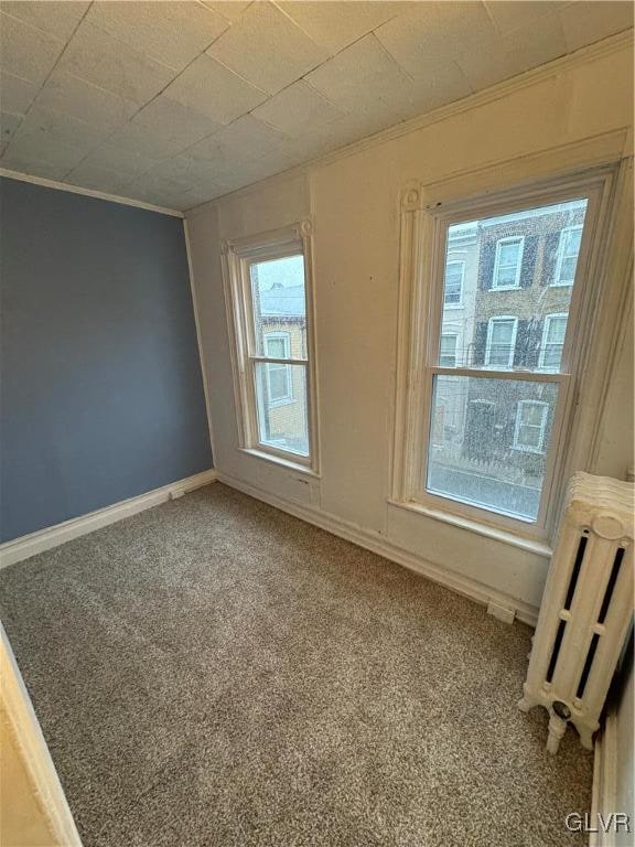 carpeted spare room featuring radiator