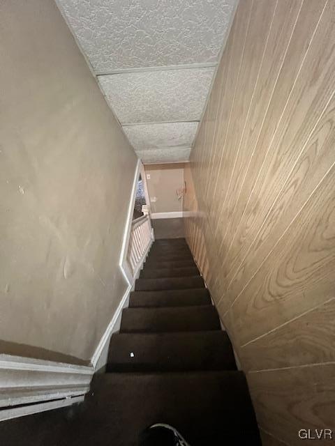 stairway featuring wood walls