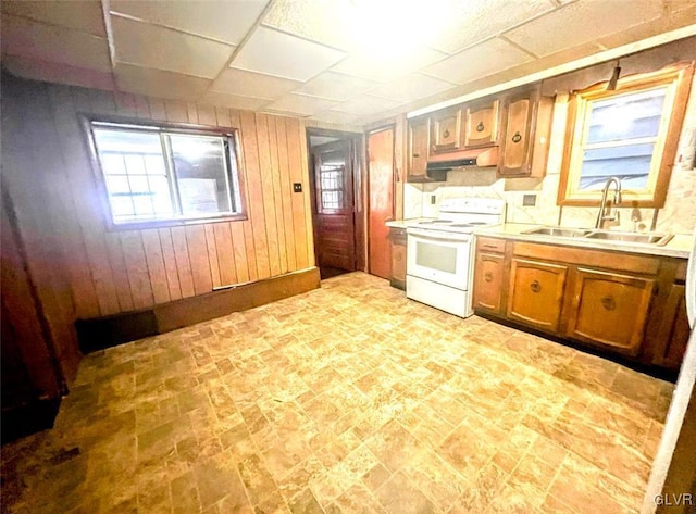 kitchen featuring white electric stove, wooden walls, and sink