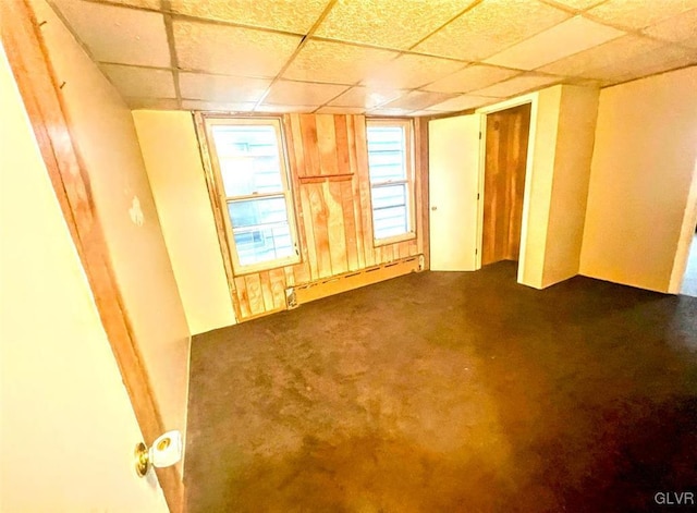 carpeted empty room with a drop ceiling and a baseboard heating unit