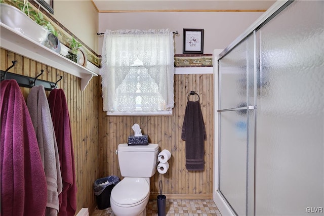 bathroom featuring wooden walls, a shower with door, and toilet