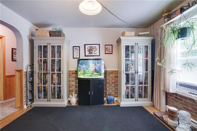 unfurnished living room with hardwood / wood-style floors, cooling unit, and wooden walls