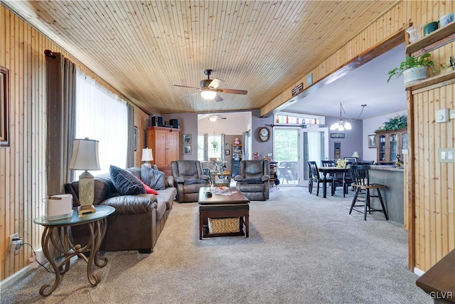 living room with carpet flooring, ceiling fan with notable chandelier, wood ceiling, and wood walls