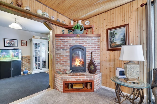 carpeted living room with wood ceiling, wooden walls, and a brick fireplace