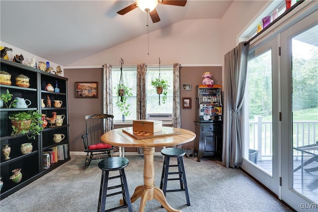 carpeted dining space with ceiling fan and vaulted ceiling