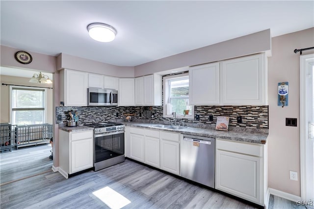 kitchen featuring stainless steel appliances, white cabinetry, tasteful backsplash, and a healthy amount of sunlight