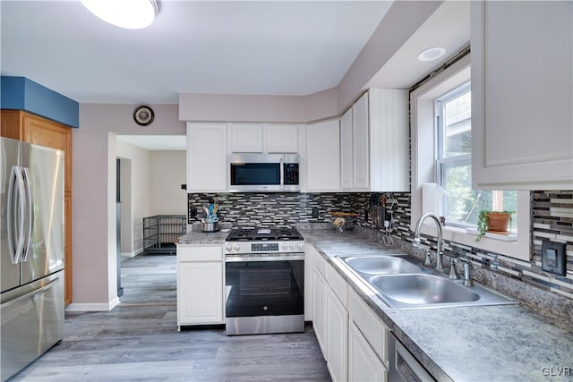 kitchen featuring sink, stainless steel appliances, decorative backsplash, white cabinets, and hardwood / wood-style flooring