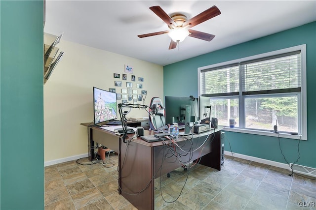 office area with baseboards, ceiling fan, and stone finish flooring